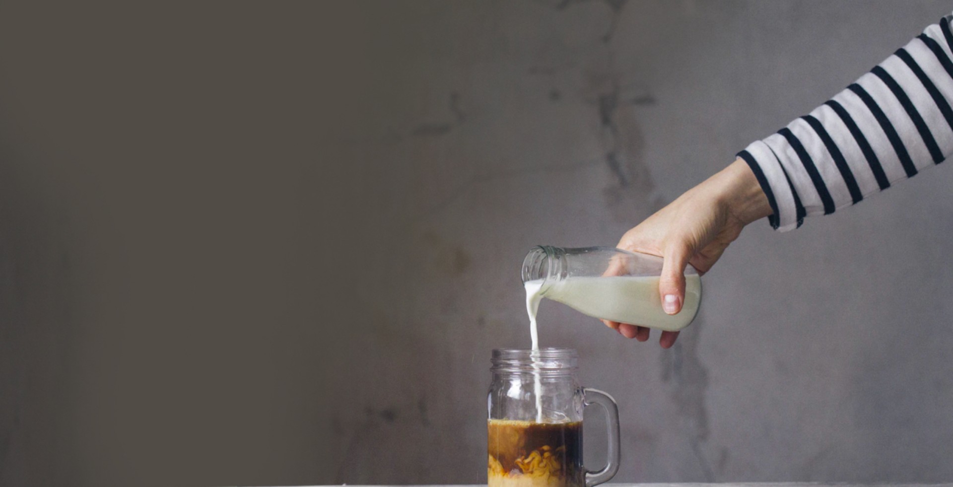 Pelayan yang menuangkan susu ke dalam gelas kopi espresso di suatu kafe modern dan minimalis di Jakarta Selatan 