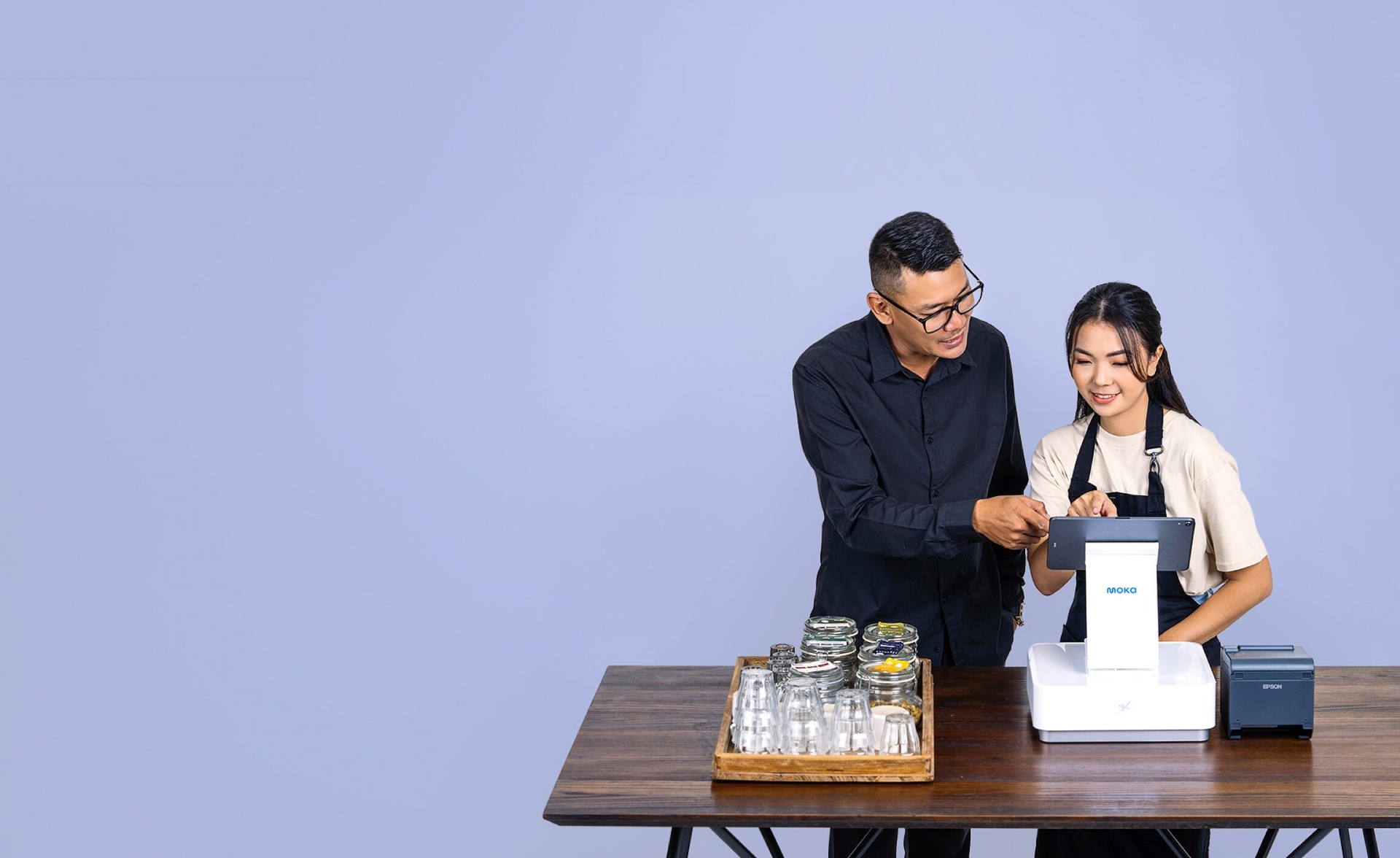 Pemilik bisnis toko kopi yang sedang memberi arahan karyawan untuk mengoperasikan Moka POS sebagai kasir yang lebih efisien